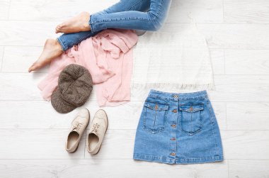 Farklı aksesuarları ve beyaz ahşap zeminde kot pantolon giymiş kadın bacaklarıyla sıradan bir yaz kıyafeti. Üst görünüm