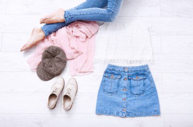 Farklı aksesuarları ve beyaz ahşap arka planda kot pantolon giymiş kadın bacaklı moda kıyafetleri. Üst görünüm