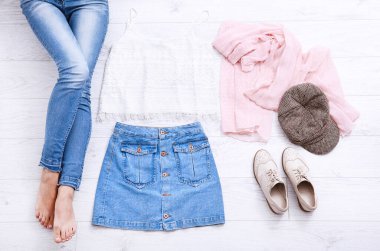 Farklı aksesuarları ve beyaz ahşap zeminde kot pantolon giymiş kadın bacaklarıyla sıradan bir yaz kıyafeti. Üst görünüm