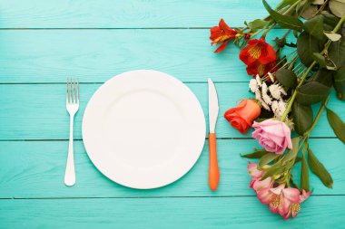Kutlama yemeği ve mavi ahşap arka planda güller. Üst Manzara. Model yap. Çiçekler.