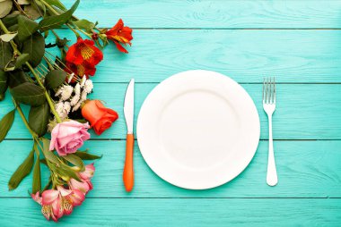 Kutlama yemeği ve mavi ahşap arka planda güller. Üst Manzara. Model yap. Çiçekler.