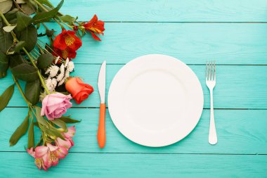 Kutlama yemeği ve mavi ahşap arka planda güller. Üst Manzara. Model yap. Çiçekler.