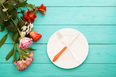 Kutlama yemeği ve mavi ahşap arka planda güller. Üst Manzara. Model yap. Çiçekler.