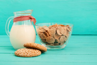 Mavi ahşap mutfakta bir sürahi sütle yulaf gevreği ve kurabiyeler. Puantiyeli masa örtüsü. Boşluğu kopyala