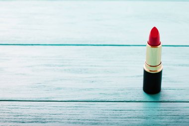 Mavi ahşap arka planda pembe ruj. Uzayı kopyala Ürün ve kozmetik konsepti uydur. Seçici odak