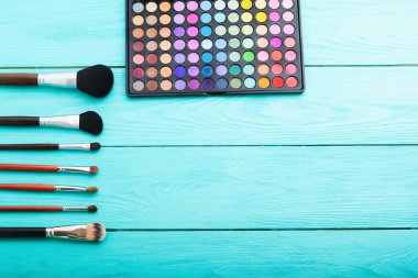 Mavi ahşap arka planda kozmetik ve aksesuarlar. Üst görünüm