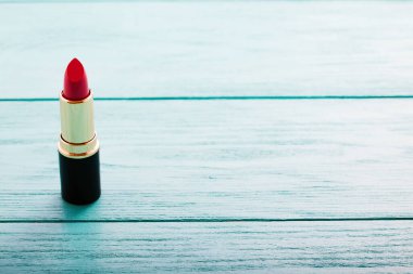 Mavi ahşap arka planda pembe ruj. Uzayı kopyala Ürün ve kozmetik konsepti uydur. Seçici odak