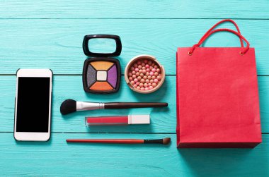 Aksesuarları uydur. Üst Manzara. Mavi ahşap arka plan. Boş ekranlı akıllı telefon. Kozmetik ürünleri.