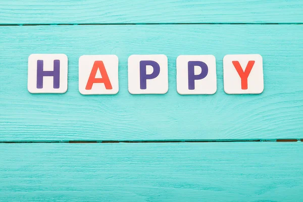 Word happy on blue wooden background. Happy emotions concept. Happiness