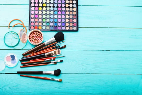 Makyaj fırçası ve ürünler. Uzayı kopyala Model yap. Mavi ahşap arka planda kozmetik ve aksesuarlar. Üst görünüm