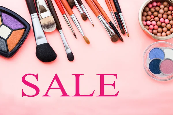 Cosmetics on pink background sale word. Top view.