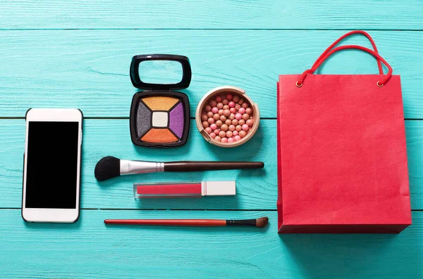 Aksesuarları uydur. Üst Manzara. Mavi ahşap arka plan. Boş ekranlı akıllı telefon. Kozmetik ürünleri.