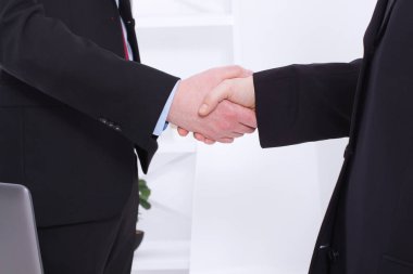 İş ortaklığı konsepti. Başarılı iş adamları ofis geçmişindeki kârlı anlaşmadan sonra el sıkışıyorlar. Takım elbiseli iş adamlarının el sıkışması. Boşluğu kopyala ve seçici odak