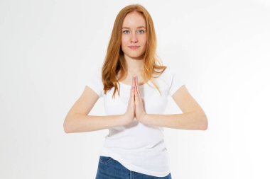 Beyaz tişörtlü güzel kızıl saçlı kadının kapalı çekimleri arka planda izole edilmiş yoga ve meditasyon yapıyor namaste Mudra 'da avuç içlerini bir arada tutuyor sakin ve huzurlu görünüyor.