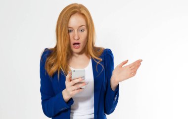 Beyaz arka planda izole edilmiş, telefonuyla gülümseyen güzel kızıl saçlı duygusal kız. İş kıyafetli genç seksi kadın, hayret verici bir görünüm sergiliyor, sağ üst köşede parmakla gösteriyor ki,.