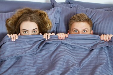 Yetişkin bir çift yatakta battaniyenin altında saklanıyor. Sabahları çift yatak odasında..