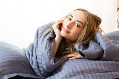 Güzel sarışın kadın yatakta yatıyor, güzel sarışın yatak odasında poz veriyor.