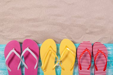 Kum kopyalama alanı. Kum arkaplan üst görünümü. Çok renkli plaj terlikleri.