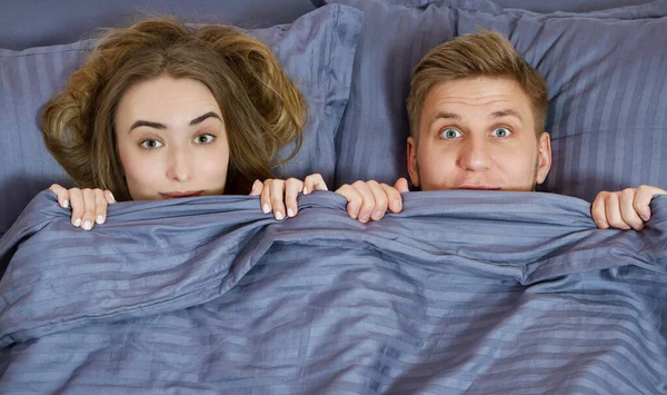 adult couple hiding under blanket in bed . Couple in bedroom in the morning.