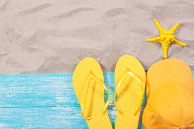 Kum kopyalama alanı. Kum arka plan üst manzara. Plaj havlusu, plaj terliği, sarı bluzer ve deniz yıldızı.