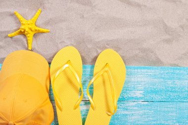 Kum kopyalama alanı. Kum arka plan üst manzara. Plaj havlusu, plaj terliği, sarı bluzer ve deniz yıldızı.