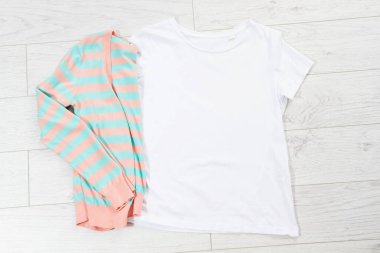 Tişört maketi, tişört üst görünümü, beyaz yakın plan tişört düz beyaz ahşap arka planda yatıyordu. Üst görünüm ve telif alanı. Model tişört ve yaz tatili. Şablon boş gömlek.