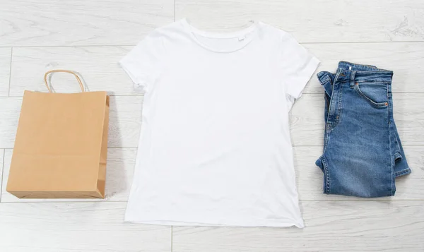 ホワイトTシャツ ブルーデニム 空の紙袋コピースペーストップビュー 女性のカジュアルのオーバーヘッドビュー — ストック写真