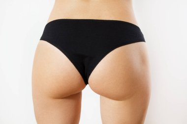Perfect female sexy buttocks isolated - Cropped close up half-turned photo of ideal elastic flawless beautiful woman's ass wearing white underlinen underclothes isolated on background.