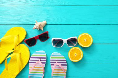 Yaz aksesuarları. Terlikler, güneş gözlükleri, havlular ve portakallar mavi ahşap arka planda. Üst görünüm
