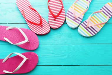 Mavi ahşap zemin üzerinde parmak arası terlikler. Üst görünüm ve boşluk kopyala. Yaz eğlenceli hafta sonu
