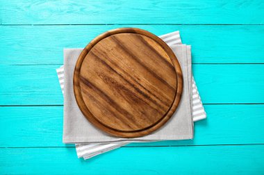 Mavi ahşap zemin üzerinde çizgili ve gri masa örtüsü olan yuvarlak kesme tahtası çerçevesi. Üst Manzara ve Anneler Günü