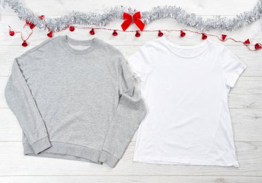 Beyaz boş şablon tişörtü, gri kapüşonlu kapüşonlu fotokopi odası ve Noel tatili konseptini kapat. Üst manzara tişörtü, beyaz ahşap arka planda kırmızı fiyonk. Mutlu yeni yıl dekorasyonları