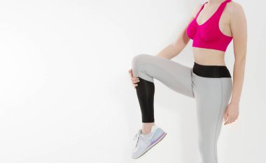 Sporcu genç kız beyaz arka planda izole giysiler giyiyor. Kilo veren kadın vücut konsepti. Atletik vücut ve yetişkin aktiviteleri. Uzayı kopyala Diz çalışması