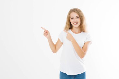 Yazlık tişört giyen gülümseyen sarışın beyaz kadının portresi beyaz şablon ve boş arkaplanda parmak izolasyonu ile fotokopi alanını işaret ediyor. Şok olmuş ve heyecanlı yüz..