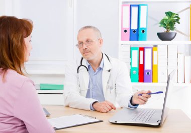 Doktor kadın hastayla konuşuyor ve sağlık ofisinde oturuyor. Beyaz üniformalı bir adam. Sağlık sigortası. Uzayı kopyala Kaliteli tıp konsepti.