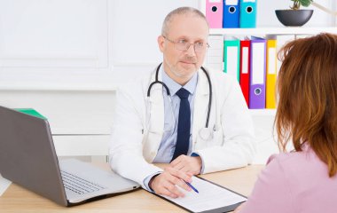 Doktor kadın hastayla konuşuyor ve sağlık ofisinde oturuyor. Beyaz üniformalı bir adam. Sağlık sigortası. Uzayı kopyala Kaliteli tıp konsepti.