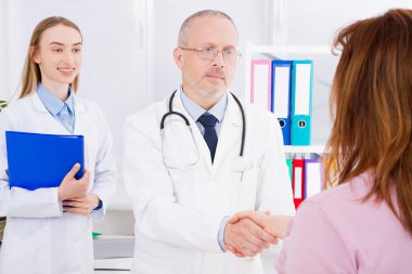 Doktor, tıbbi personelle birlikte ofiste poz veriyor. Steteskop takıyor. Kaliteli tıp konsepti. Beyaz üniformalı adam. Sağlık sigortası. Seçici odaklanma. Boşluğu kopyala