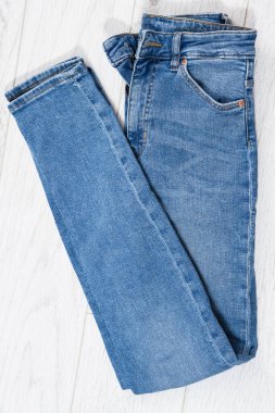 Beyaz ahşap arka planda katlanmış mavi kot, açık ahşap arka planda katlanmış kot - üst görünüm