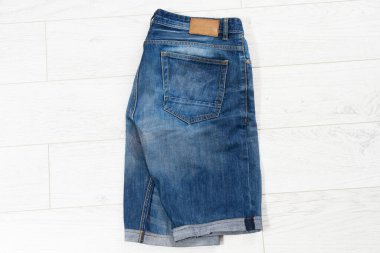 Katlanmış kot şortlar izole edilmiş. Beyaz ahşap arka planda izole edilmiş çocuk için modaya uygun kotlar. Modaya uygun kot pantolon..