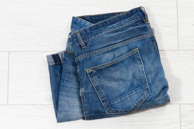 Beyaz ahşap arka planda katlanmış mavi kot, açık ahşap arka planda katlanmış kot - üst görünüm