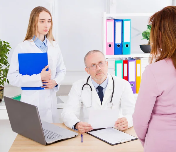 Doctor is talking with woman patient and sitting in medical office.Man in white uniform. Medical insurance. Copy space. Quality medicine concept.
