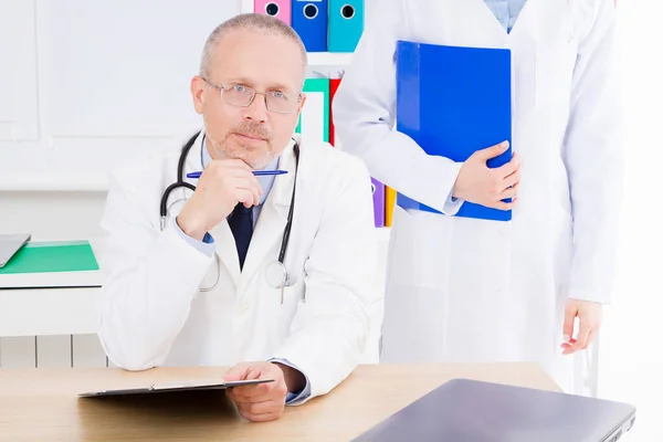 Doctor Posando Consultorio Con Personal Médico Que Está Usando Estetoscopio —  Fotos de Stock