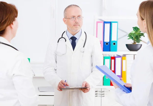Doctor Posando Consultorio Con Personal Médico Que Está Usando Estetoscopio —  Fotos de Stock