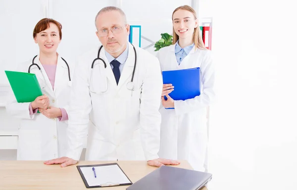 Doctor Posando Consultorio Con Personal Médico Que Está Usando Estetoscopio —  Fotos de Stock