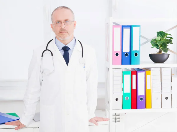Portrait of senior doctor in medical office.Man in white uniform. Medical insurance. Copy space. Quality medicine concept. Copy space