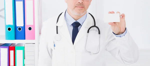 doctor in hospital hold business card, medical insurance, man in white uniform. Copy space
