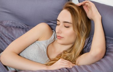 Güzel genç bir kadın yatakta uyuyor. Rahat uyu.