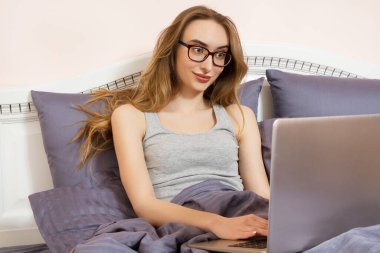 Yatak odasında dizüstü bilgisayarda çalışan genç ve güzel Asyalı kadın. Satış, menajer, serbest çalışan.