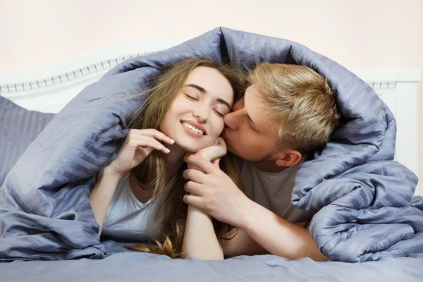 Young beautiful couple kissing in bed in the morning in the bedroom, young happy couple, family values.