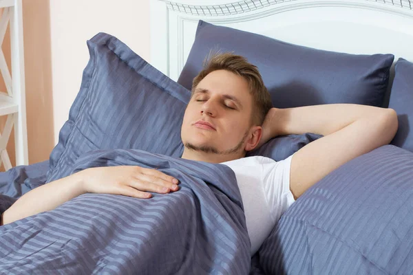 Young man sleeping in bed alone at home